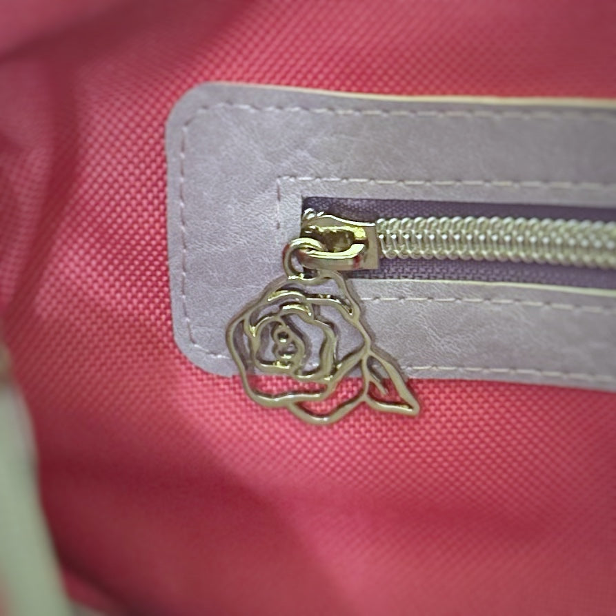 Close-up of the interior zipper pocket on a handmade tote bag, featuring a lavender faux leather trim and a silver zipper with a gold rose-shaped zipper pull. The background is a vibrant pink fabric lining.